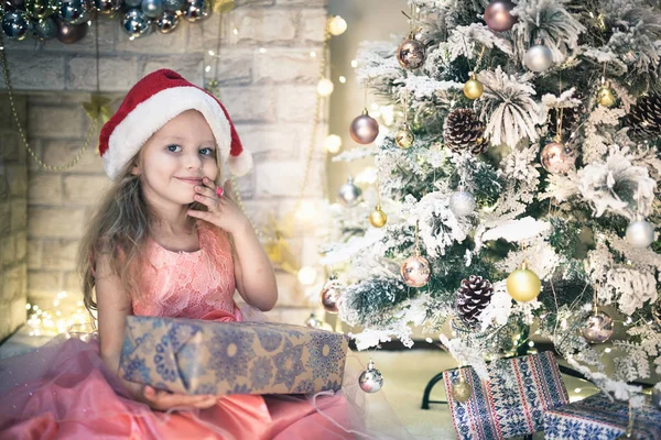 Menina feliz criança descompacta seu presente na noite de Natal . — Fotografia de Stock