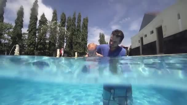 Glücklich lächelndes Kleinkind taucht mit Vater unter Wasser — Stockvideo