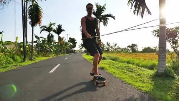 Skateboarder equitazione lungo la strada vicino belle terrazze di riso, Bali — Video Stock