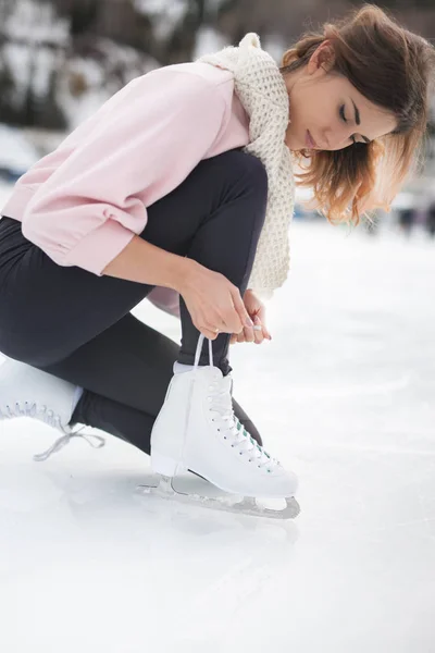 Mulher amarrar cadarços figura patins na pista de gelo close-up — Fotografia de Stock
