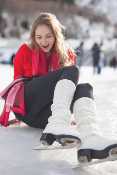 Happy girl sitting at ice. Woman ice skating outdoor