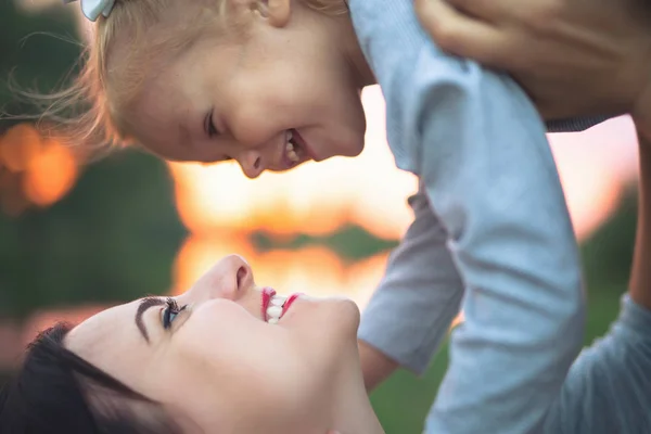 Schöne junge Frau und ihre charmante kleine Tochter umarmen sich Stockfoto