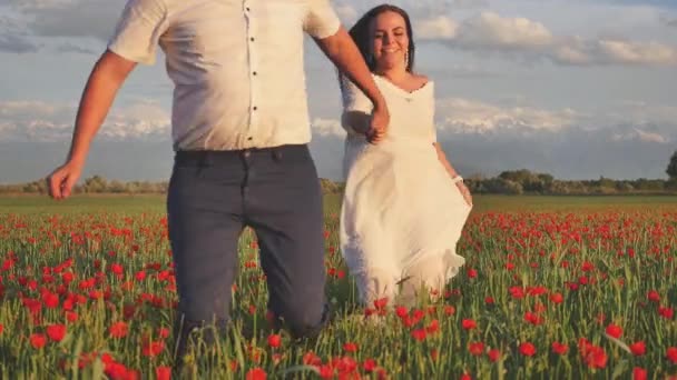 Záběry z novomanželé legrační pár běží přes pole s květinami — Stock video