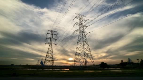 時間の経過 映像のサンセットで つ伝送送電線鉄塔水田では前景としてフィールドします 移動と夕日として雲の色を変更します — ストック動画