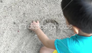 Asya (melayu) Malezya çocuk iskambil kum bir plajda ağır çekim görüntüleri.