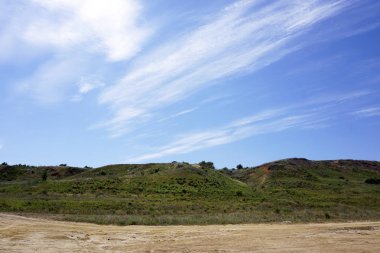 Exposured bulutların üzerinde yeşil tepe ve kumlu plaj, yaz