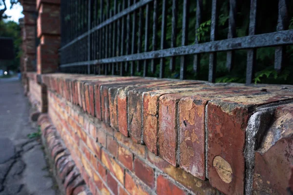 Red brick fence wall background with metal fence.