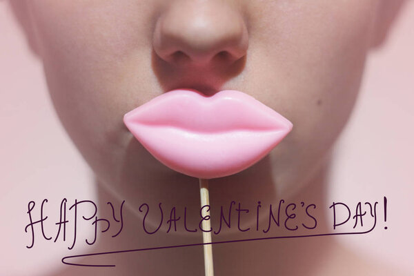 Красота веселая молодая смешная модель Девушка, держащая большие розовые губы на палке улыбаясь, Концепция красоты. На розовом фоне. Фронтальный вид
