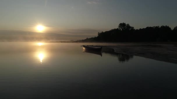 En la orilla del lago Svityaz, un barco de madera se encuentra con el sol en la niebla . — Vídeo de stock