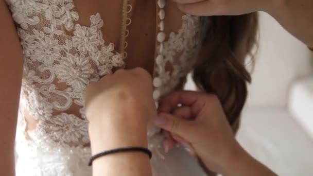 Las manos femeninas abrochan los botones sobre el vestido de boda. — Vídeo de stock