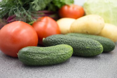 Gri bir atölyede taze sebzeler, yakın plan: patates, yeşil soğan, dereotu, domates, maydanoz. Sağlıklı yemek, vejetaryen yemeği..