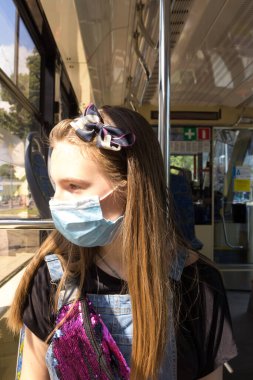 Genç bir kız covid-19 salgını sırasında tıbbi maske takıyor.