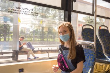 Genç bir kız covid-19 salgını sırasında, Moskova tramvayı sırasında tıbbi maske takıyor.