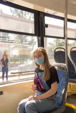 Genç bir kız covid-19 salgını sırasında, Moskova tramvayı sırasında tıbbi maske takıyor.