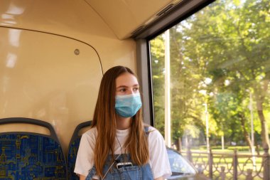 Otobüste maskeli bir kız. Koronavirüs salgınından dolayı zorunlu maske takma dönemi. 