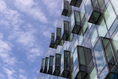 Modern mimarinin bir parçasını soyutla, mavi bulutlu gökyüzünün arka planında balkonlu cam duvarlar..