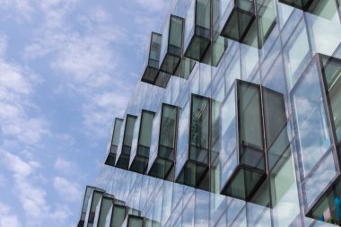 Modern mimarinin bir parçasını soyutla, mavi bulutlu gökyüzünün arka planında balkonlu cam duvarlar..