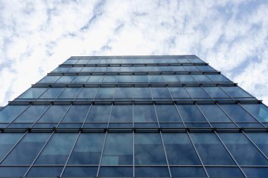 Modern mimarinin bir parçasını soyutla, mavi bulutlu gökyüzünün arka planında camdan duvarlar.