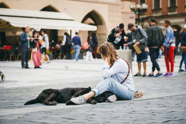 Çek Cumhuriyeti, Prag, 25 Temmuz 2017: Bir güzel genç kadın ressam pistinin ortasında kare ve berabere, ona yalan büyük siyah bir köpek bir kucaklama içinde oturur. Birçok kişi arka plan.