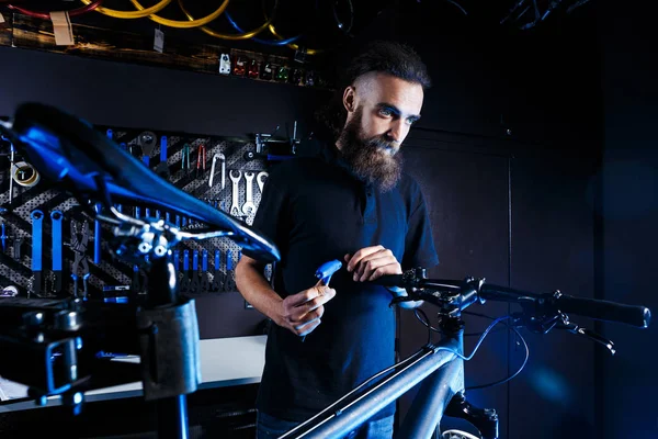 Tema satış ve bisiklet tamiri. Genç ve şık uzun saç ve sakal ile bir beyaz adam bir araç ayarlamak ve bir mağaza bir bisiklet onarmak için kullanır. İş yerinde iş sahibi.