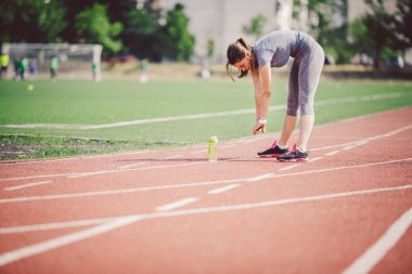 Kuyruk ve egzersizleri yapıyor, ısınma ve eğitim güneşli bir yaz aylarında çalışan Stadyumu, Kırmızı lastik parça önce kasları ısınma büyük göğüsler uzun saçlı güzel genç bir beyaz kadın.