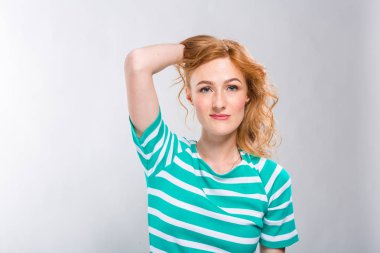 Mavi gri bir arka plan üzerinde stüdyoda şeritler ile yakın çekim portre bir yazlık elbise kırmızı kıvırcık saçlı genç, güzel bir kadının. Yaz tatil, turizm ve yaz giysileri Tema