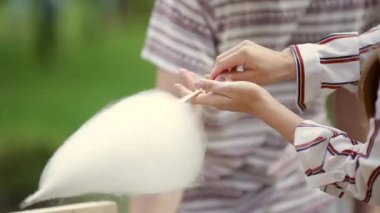 Video Tema tatlılar yemek küçük bir iştir. Bir önlük tüccar şapkalı olan beyaz bir kadın çıkış sahibi bir helva, bir peri ipi veya pamuk helva yapar yaz parkta