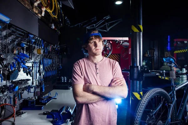 中小企業と自転車輸送サービス 自転車のワーク ショップ 設定および修復ツールの背景にポーズ キャップで若い男の肖像 — ストック写真