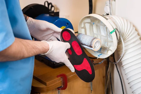 The process of manufacturing orthopedic individual insoles for people with leg diseases, flat feet. Close-up of a man\'s hand of an employee urges an orthopedic insole on a machine tool in a workshop.