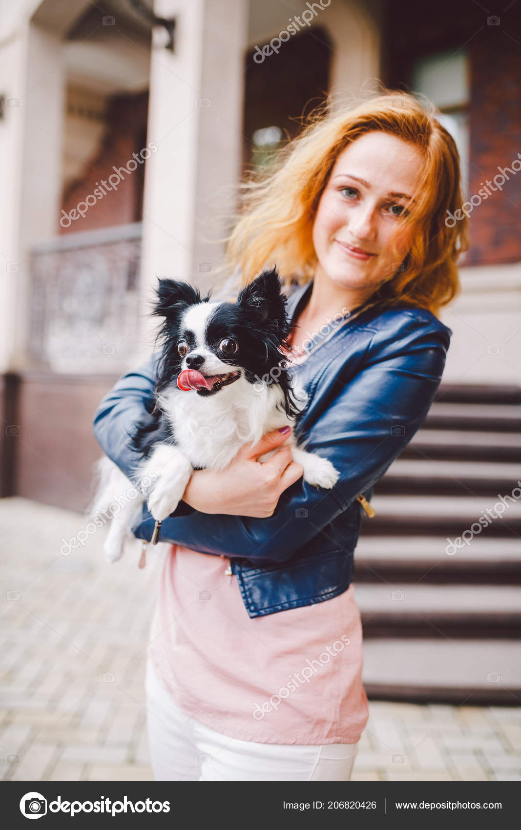 A Beautiful Young Woman With Red Long Hair Is Holding A Small