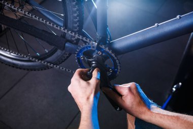 Bir erkek Bisiklet tamircinin el atölye bir close-up ayarlamak ve bisiklet krank derleme bisiklet deposu açık bisiklet yıldızlarda onarmak için bir tornavida aracı kullanır