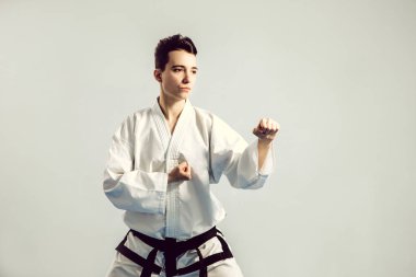 Kız karate gri arka planı stüdyosunda kimono uygun. Kadın çocuk judo veya karate gösterir beyaz siyah kuşak ile Tekdüzen stans. Bireysel savaş sanatı spor. Tam vücut portre