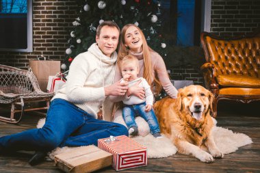 Tema Noel ve yeni yıl aile çevresi ve yerel evde beslenen hayvan. Köpek Noel ağacı hediyeler ve büyük yakın katta oturan anne baba ve çocuk 1 yaşında beyaz bir kadın doğurmak golden labrador geri almak.