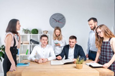 İş ve ekip çalışması temasıdır. İşçilerin bir grup brifing, çalışma kağıtları ve ahşap bir masa etrafında ışık Office belgeleri ile bir toplantı, Genç beyaz insanlar office.