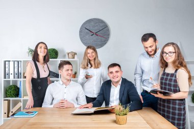İş ve ekip çalışması temasıdır. İşçilerin bir grup brifing, çalışma kağıtları ve ahşap bir masa etrafında ışık Office belgeleri ile bir toplantı, Genç beyaz insanlar office.