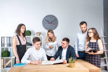 İş ve ekip çalışması temasıdır. İşçilerin bir grup brifing, çalışma kağıtları ve ahşap bir masa etrafında ışık Office belgeleri ile bir toplantı, Genç beyaz insanlar office.