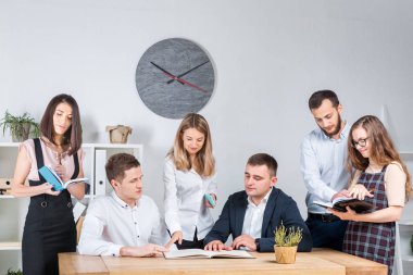 İş ve ekip çalışması temasıdır. İşçilerin bir grup brifing, çalışma kağıtları ve ahşap bir masa etrafında ışık Office belgeleri ile bir toplantı, Genç beyaz insanlar office.