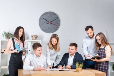 İş ve ekip çalışması temasıdır. İşçilerin bir grup brifing, çalışma kağıtları ve ahşap bir masa etrafında ışık Office belgeleri ile bir toplantı, Genç beyaz insanlar office.