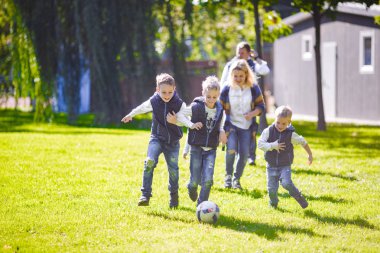 Tema aile açık hava etkinlikleri. altı anne baba büyük dostu beyaz ailesi ve dört çocuk futbol topu ile çim üzerinde çalışan, güneşli bir günde evin yanında çim çim yeşil.