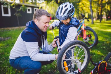 Babalar günü beyaz baba ve arka bahçesinde 5 yaşındaki oğlu bir bisiklet tamir çim yeşil çimlere şirketten bir bisiklet tekerleği pompalama yakın. Baba Çocuk Bisiklet tamir öğretir.
