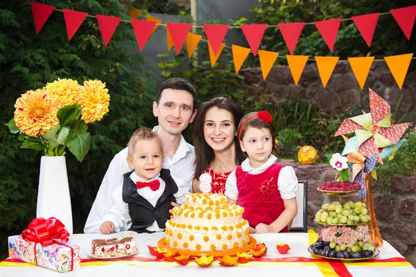 Familj av fyra personer far Mamma son och dotter firar döttrar födelsedag tre år sitter på en festlig dekorerad bordsdekor och en stor läcker tårta — Stockfoto