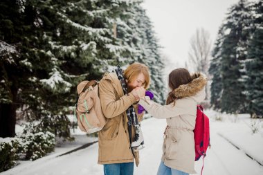 Genç çift kışın tarih. Genç beyaz adam elinde tutan uzun saç ve sakal ile örme eldiven ile kızın elleri ve ısınma ve onları Kışın kar parkta öpüşme Sevgililer günü.