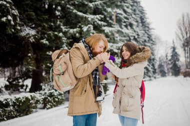 Genç çift kışın tarih. Genç beyaz adam elinde tutan uzun saç ve sakal ile örme eldiven ile kızın elleri ve ısınma ve onları Kışın kar parkta öpüşme Sevgililer günü.