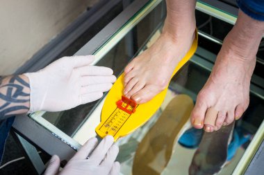 Ortopedi ve Tıp. Genç beyaz doktor el adam dövme lateks eldiven boyutu ölçüm şekli bireysel ortopedik ayakkabı astarı imalatı için ayak. Aynasız ve ayak hastalıkları.