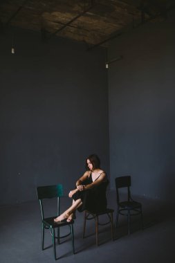 Sosyal Tema kadın yalnızlık acı acı. Abastration erkek şiddet aile. Büyük karanlık odada üç sandalyelere oturan siyah giysili genç güzel beyaz kadın. Srach ve umutsuzluk.