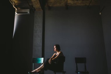 Sosyal Tema kadın yalnızlık acı acı. Abastration erkek şiddet aile. Büyük karanlık odada üç sandalyelere oturan siyah giysili genç güzel beyaz kadın. Srach ve umutsuzluk.