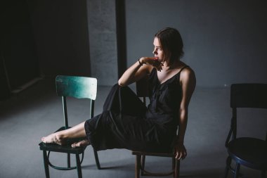 Sosyal Tema kadın yalnızlık acı acı. Abastration erkek şiddet aile. Büyük karanlık odada üç sandalyelere oturan siyah giysili genç güzel beyaz kadın. Srach ve umutsuzluk.