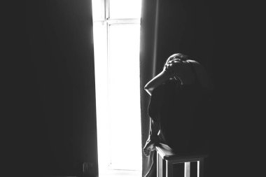 Sosyal Tema kadın yalnızlık acı acı. Abastration erkek şiddet aile. Büyük karanlık odada üç sandalyelere oturan siyah giysili genç güzel beyaz kadın. Srach ve umutsuzluk.