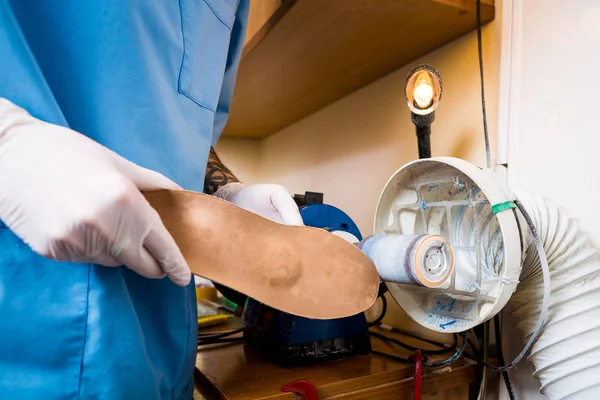 The process of manufacturing orthopedic individual insoles for people with leg diseases, flat feet. Close-up of a man\'s hand of an employee urges an orthopedic insole on a machine tool in a workshop.