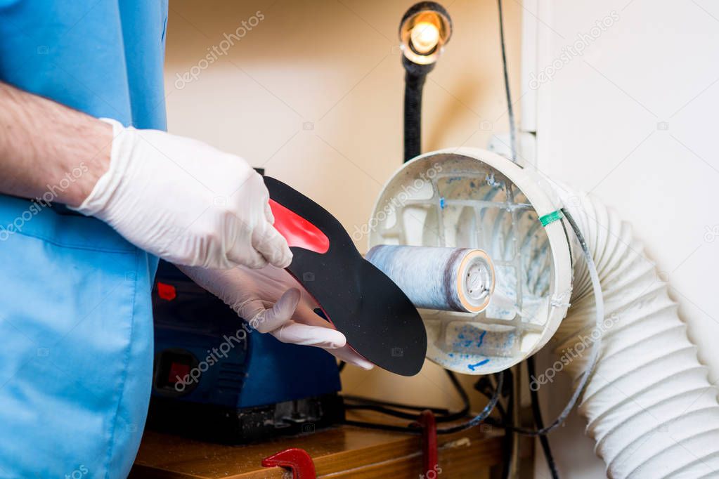 The process of manufacturing orthopedic individual insoles for people with leg diseases, flat feet. Close-up of a man's hand of an employee urges an orthopedic insole on a machine tool in a workshop.